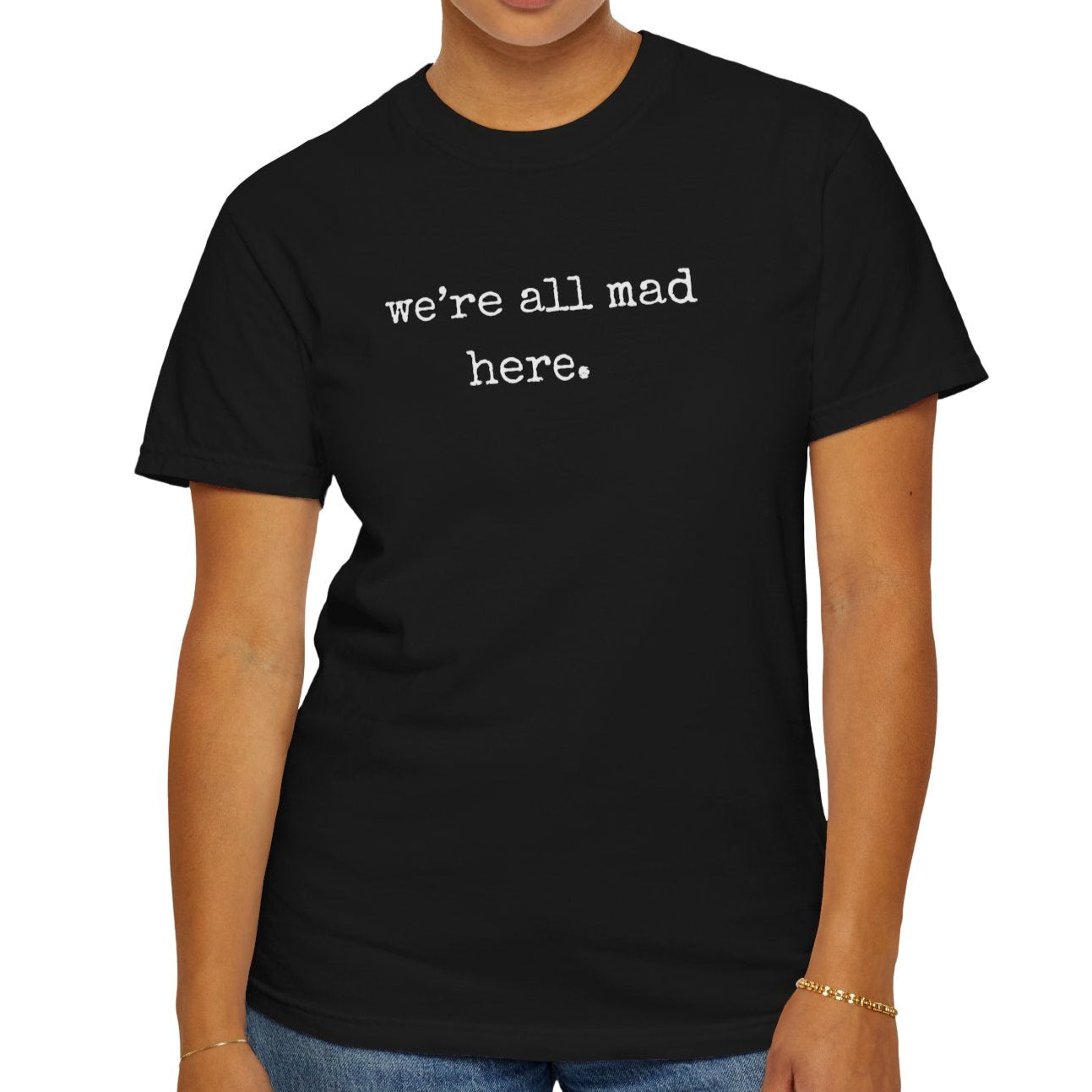 Person wearing a black t-shirt with 'we're all mad here.' text on a white background