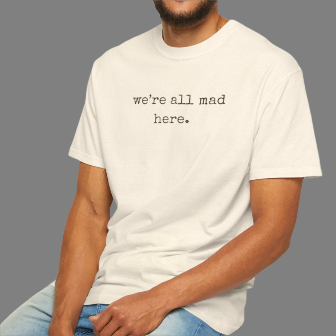 Man sitting on a stool wearing a white t-shirt with text, on a plain background