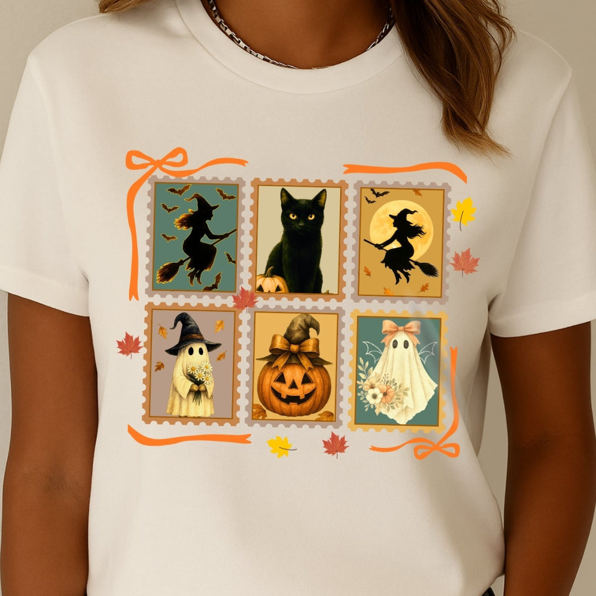 Person wearing a white t-shirt with Halloween-themed design featuring witches, cats, ghosts, and pumpkins.