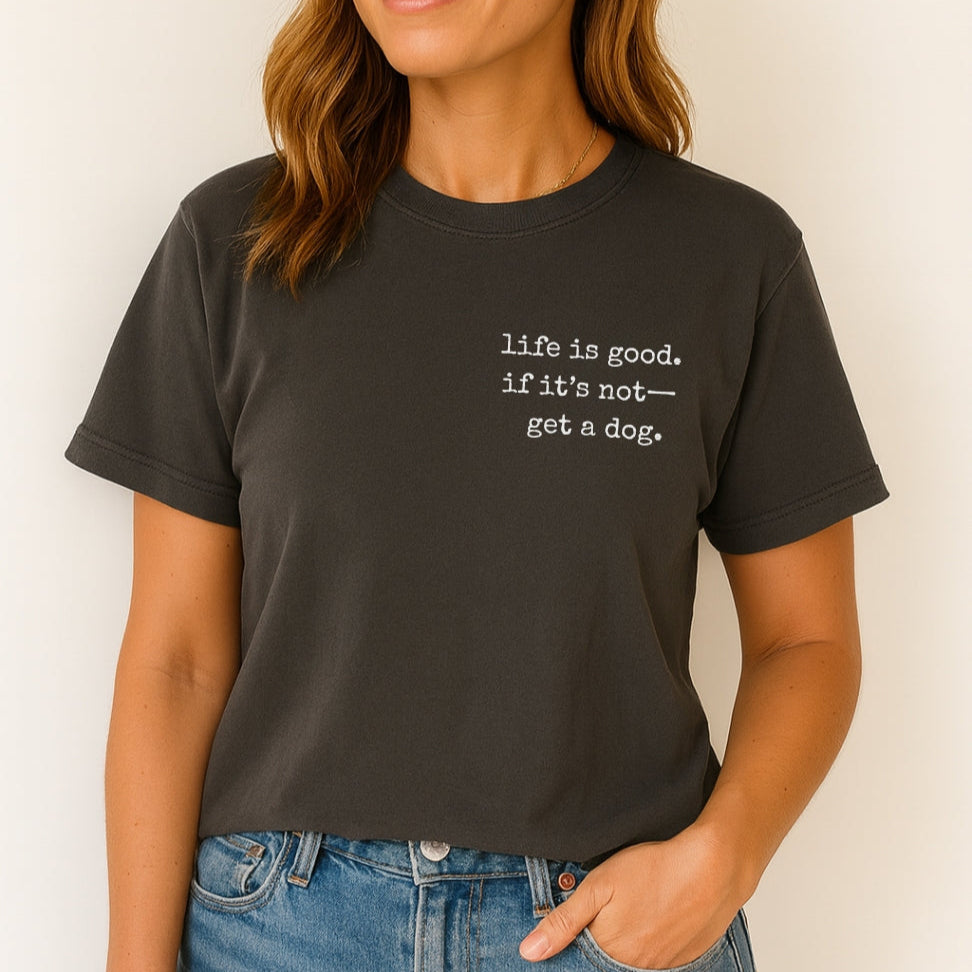 Person wearing a black t-shirt with 'life is good. if it's not-- get a dog.' text on a plain background