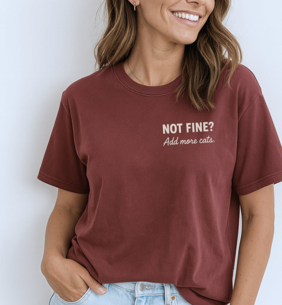 Person wearing a maroon t-shirt with text, standing against a plain background
