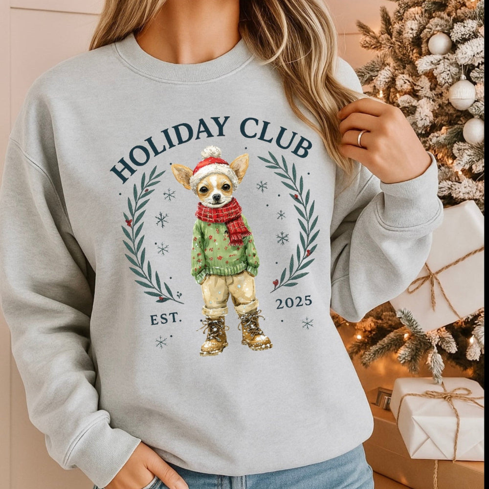Person wearing a gray sweatshirt with a Christmas-themed design in front of a decorated tree.