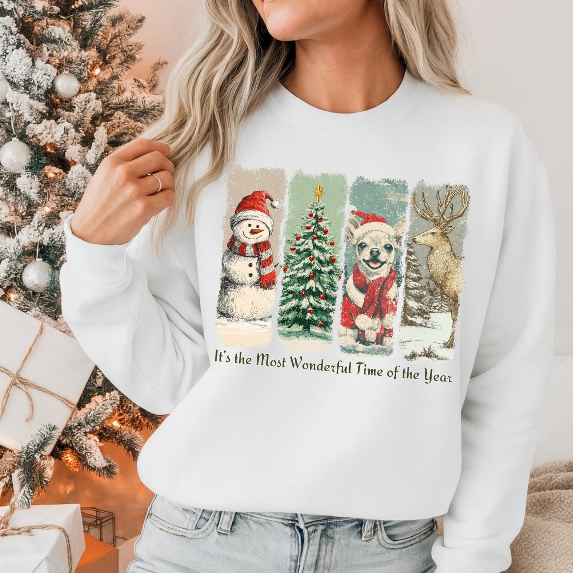 Person wearing a white sweater with Christmas-themed design in front of a decorated Christmas tree.