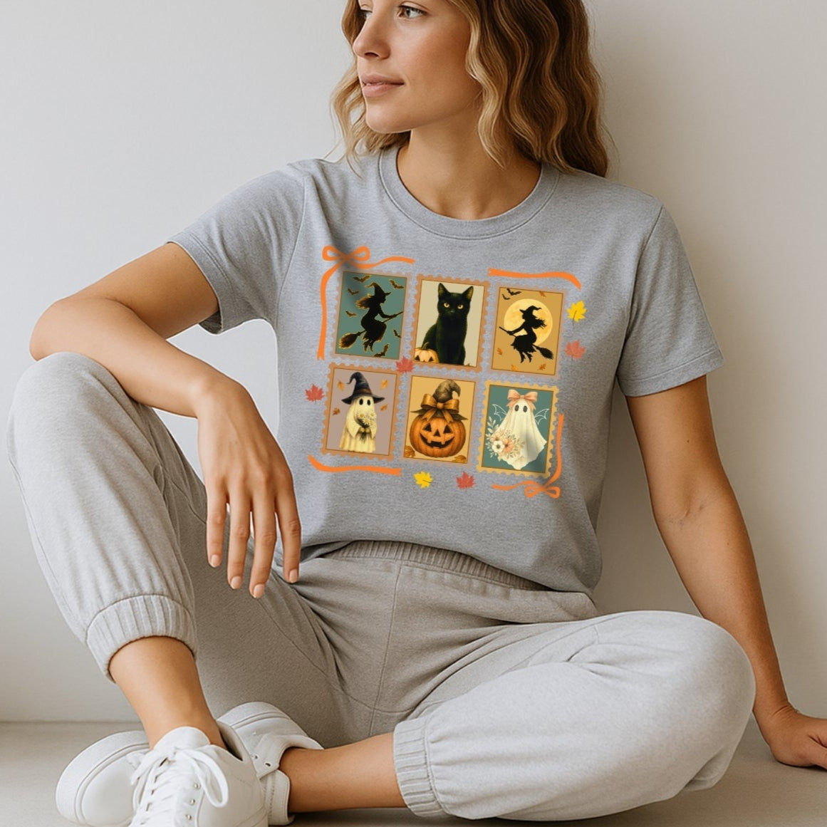 Woman wearing a gray t-shirt with a graphic design sitting on a light-colored floor.