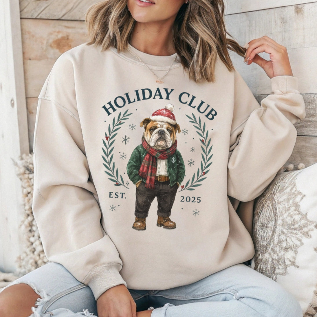 Person wearing a beige sweatshirt with a 'Holiday Club' graphic featuring a dog in a scarf.