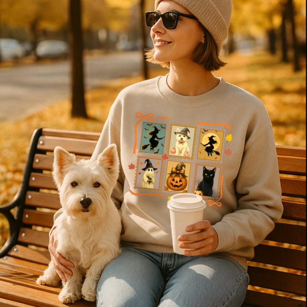 Person wearing a sand color halloween westie lover sweater sitting on a bench with a dog, holding a coffee cup, in an autumn setting.