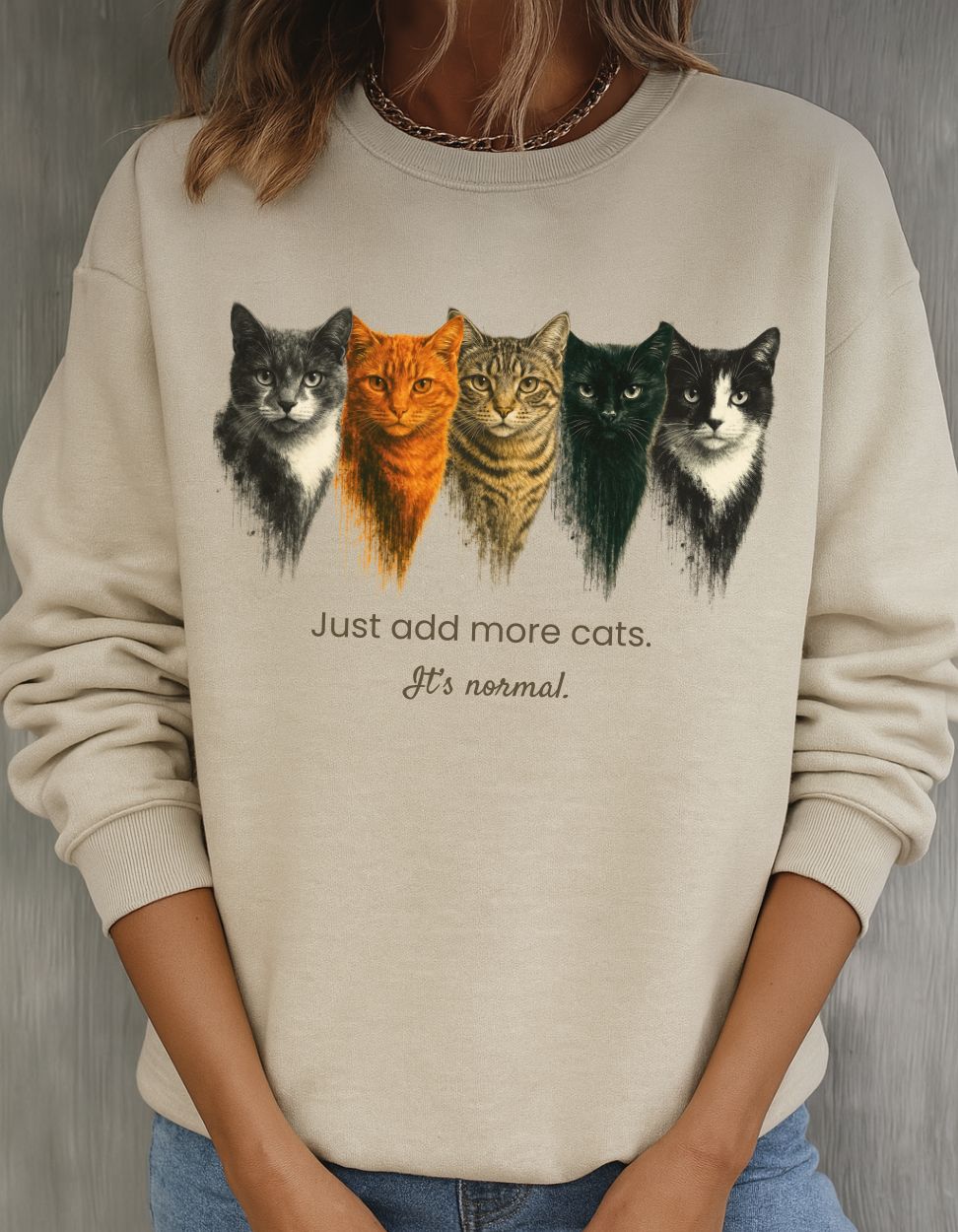 Sand sweatshirt with cat illustrations and text on a neutral background