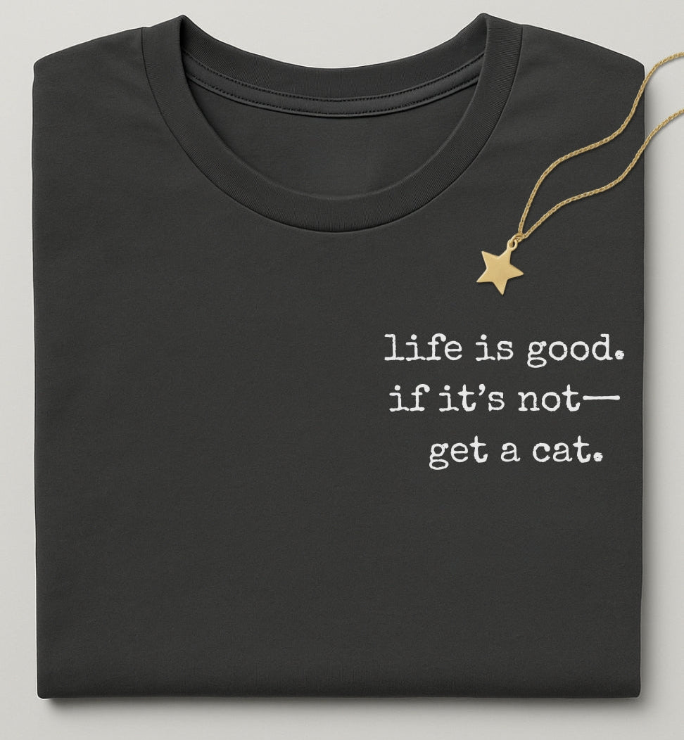 Black t-shirt with 'life is good, if it's not... get a cat.' text and a gold necklace on a light gray background