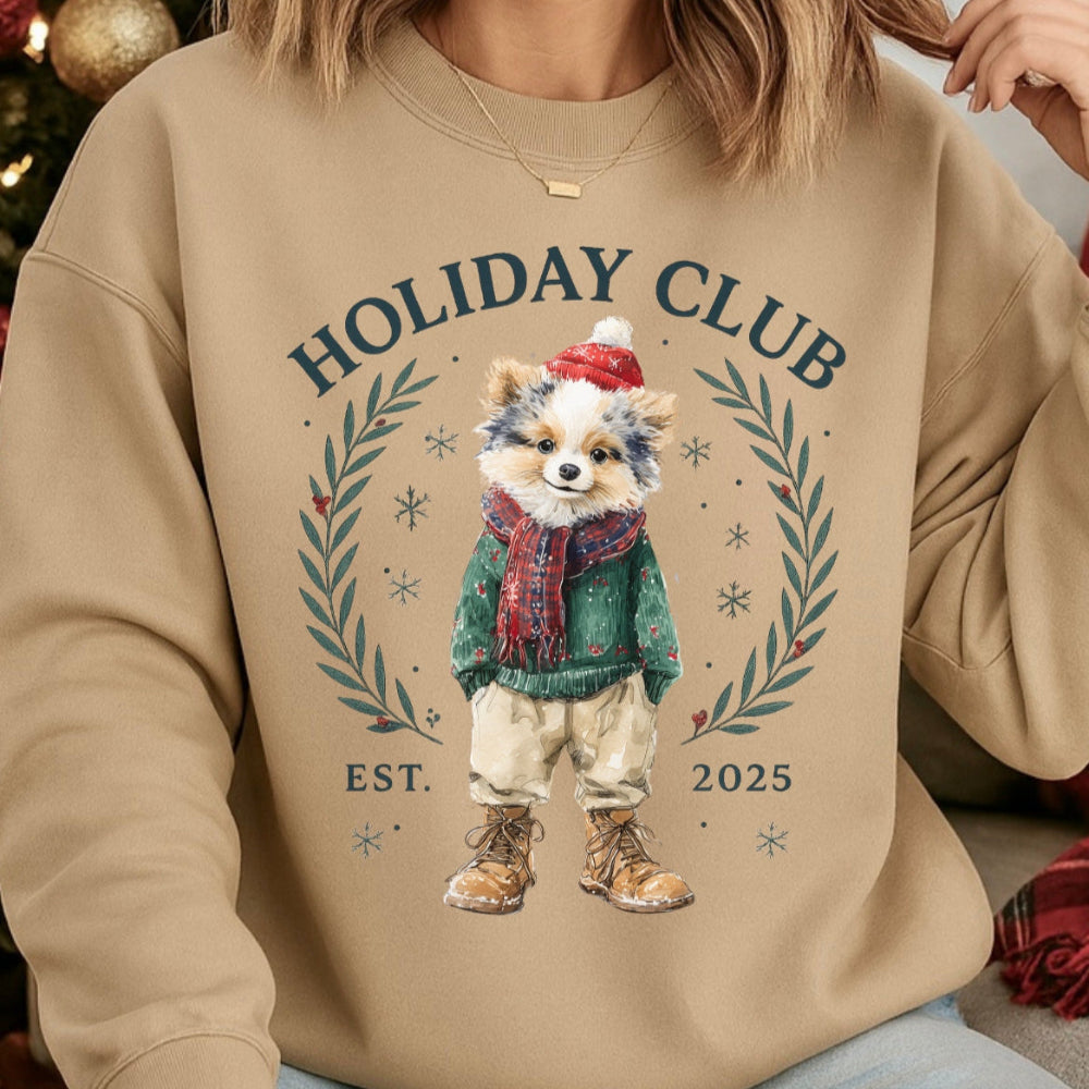 Beige sweatshirt with a festive design of a dog in winter clothing and 'Holiday Club' text.
