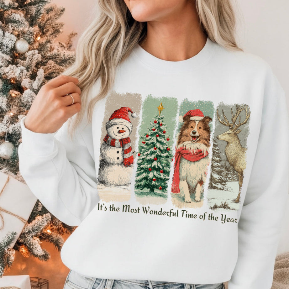 Person wearing a white sweatshirt with Christmas-themed designs and text, sitting in front of a decorated Christmas tree.