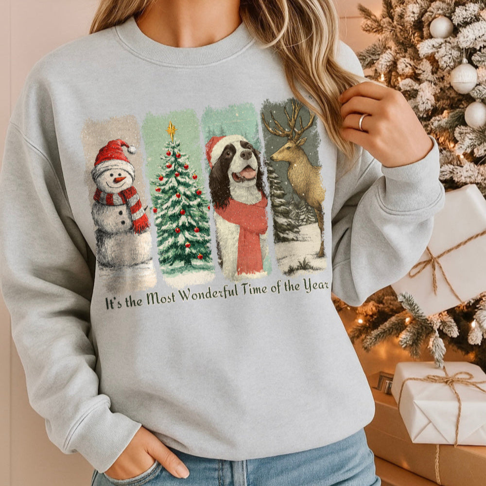 Person wearing a Christmas-themed sweatshirt with festive graphics in front of a decorated Christmas tree.
