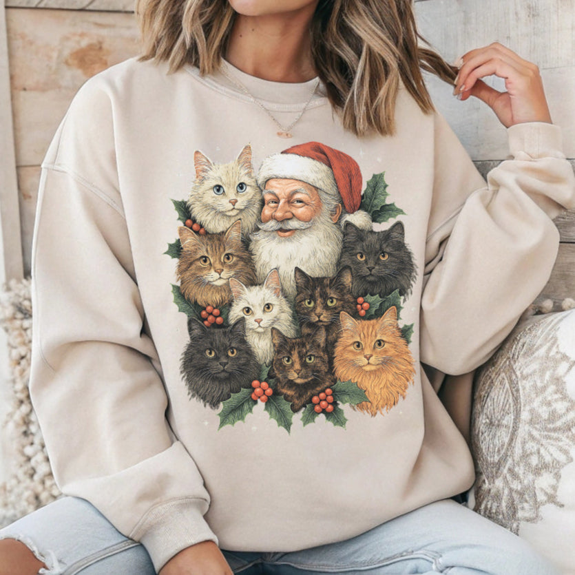 Person wearing a beige sweatshirt with a Christmas-themed design of Santa Claus and cats.