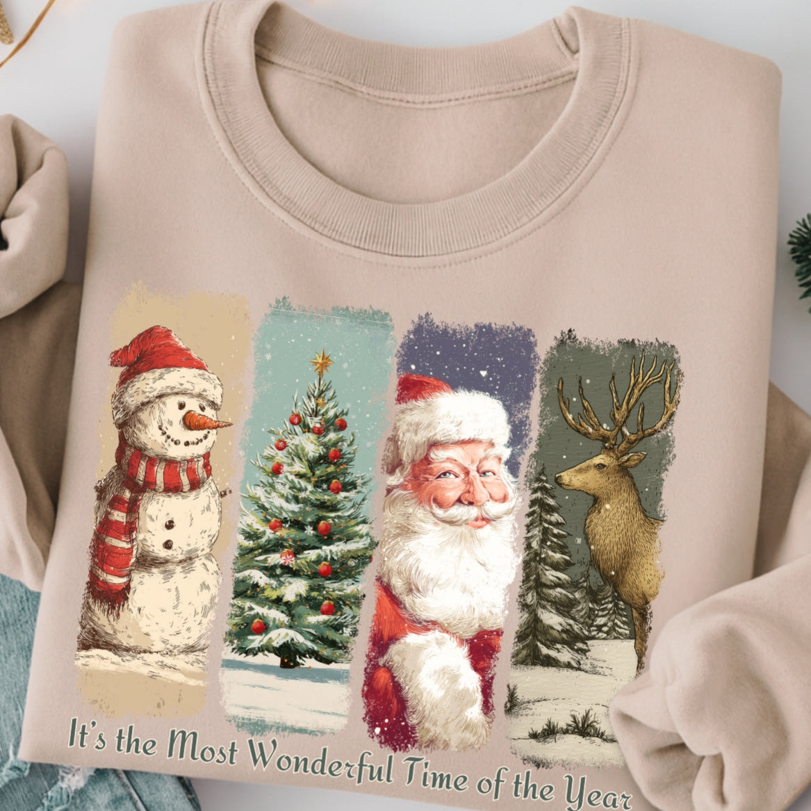 Beige sweatshirt with Christmas-themed design featuring Santa Claus, snowman, and reindeer on a white background.