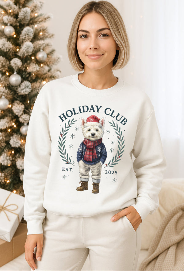 Woman wearing a white sweatshirt with a holiday-themed design in front of a decorated Christmas tree.
