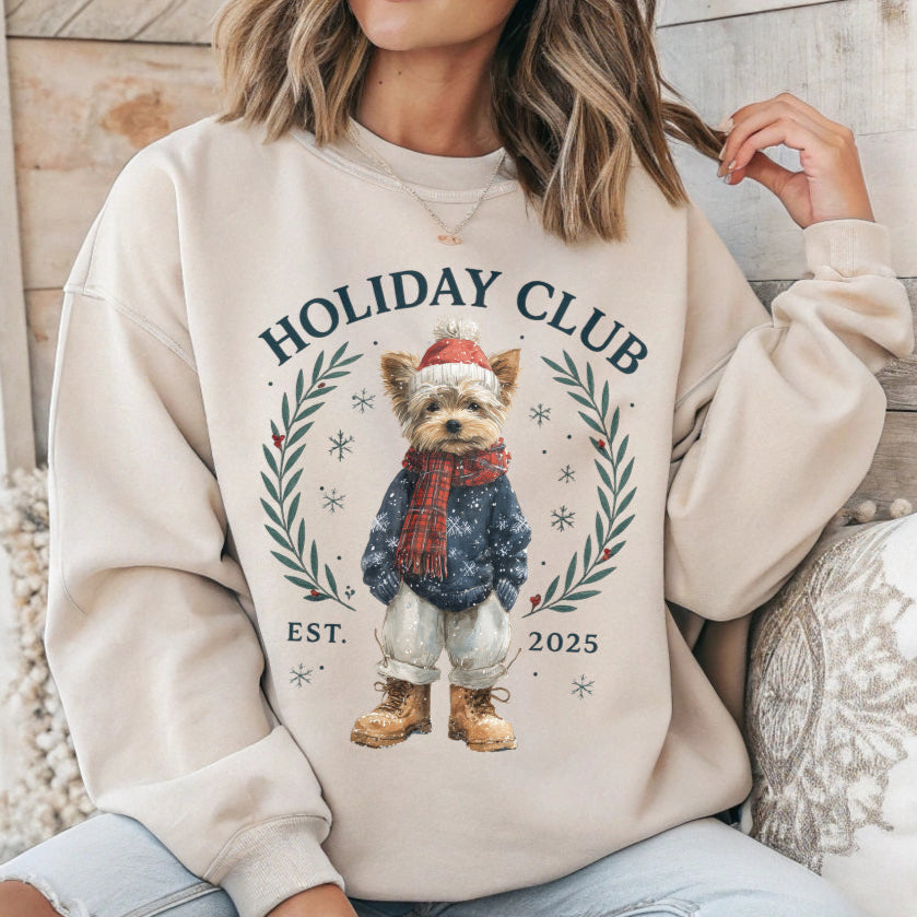 Person wearing a beige sweatshirt with a dog graphic and 'Holiday Club' text.