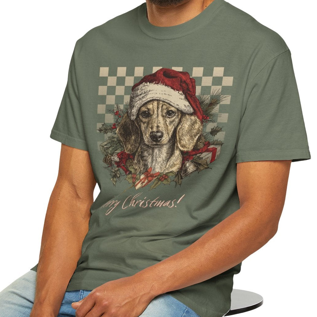 Man wearing a green t-shirt with a dog graphic and text, sitting on a stool against a white background