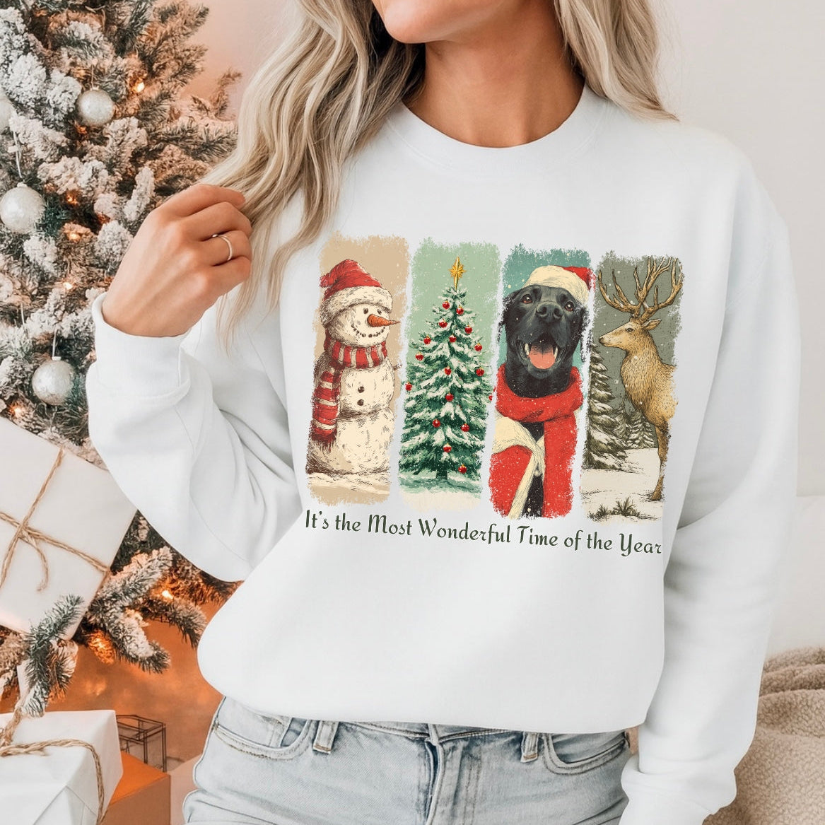 Person wearing a white sweatshirt with Christmas-themed design in front of a decorated Christmas tree.