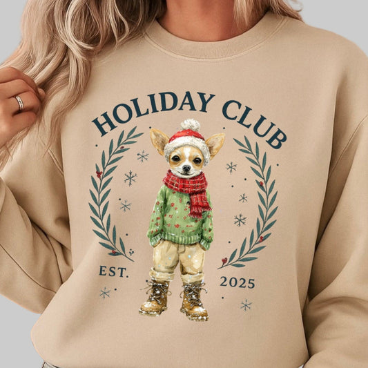Person wearing a beige sweatshirt with 'Holiday Club' design, sitting in front of Christmas decorations.