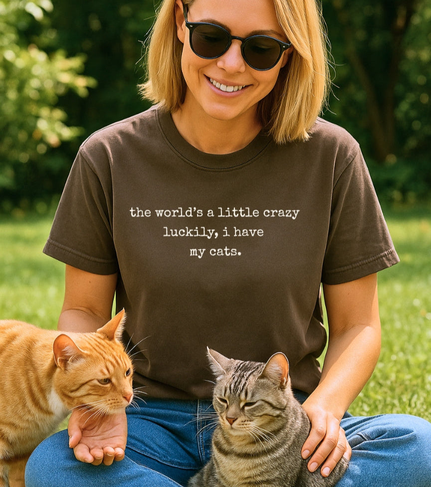 Woman sitting on grass with two cats wearing comfort colors 1717 espresso color t-shirt with text.