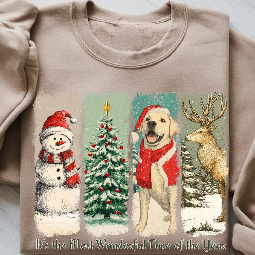 Beige sweatshirt with Christmas-themed illustrations of a snowman, tree, dog, and deer on a light wooden surface.